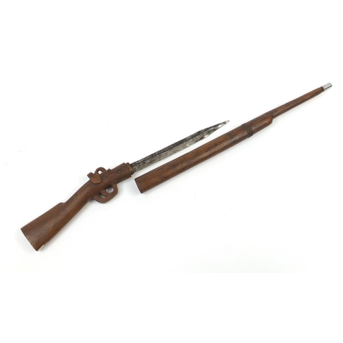 899 - African carved wood sword stick in the form of a rifle, 86cm in length