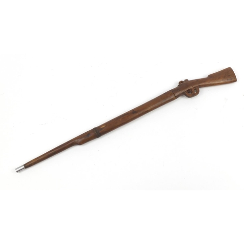 899 - African carved wood sword stick in the form of a rifle, 86cm in length