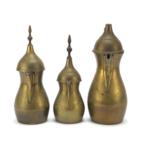 1980 - Graduated set of three Omani brass coffee pots, engraved marks to the bases, largest 18cm high