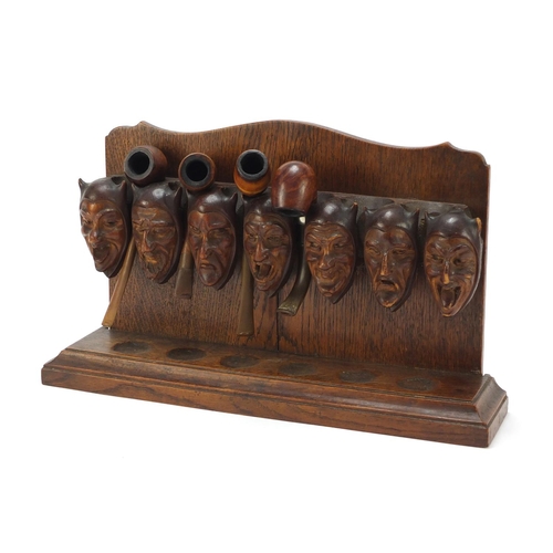 54 - Carved oak devil head design pipe stand with four pipes including two with silver mounts, the rack 3... 