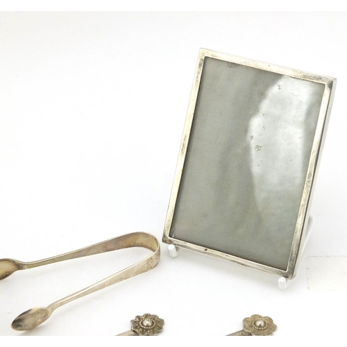 761 - Silver and white metal objects including two miniature photo frames, sugar tongs and teaspoons, vari... 