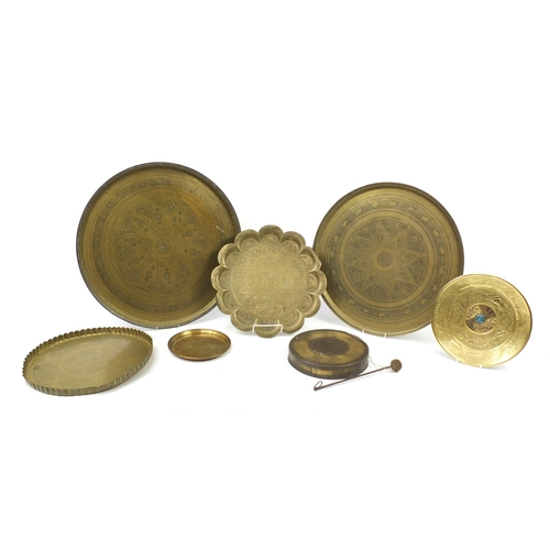 2002 - Six Middle Eastern brass trays and a gong, each engraved/embossed with figures and wild animals, the... 