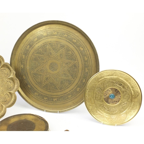 2002 - Six Middle Eastern brass trays and a gong, each engraved/embossed with figures and wild animals, the... 