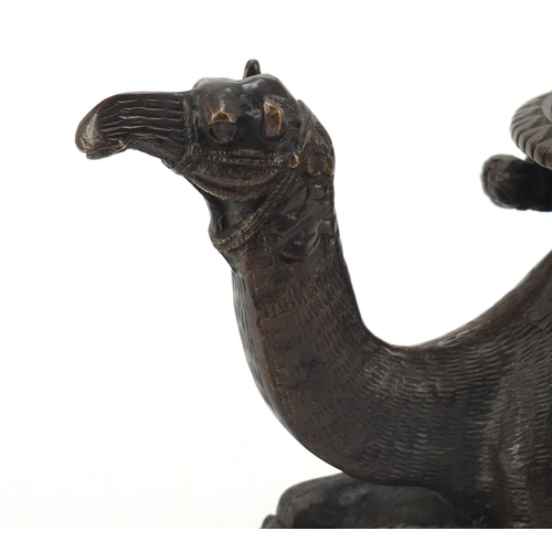 95 - Bronze model of a crouching camel raised on oval stepped base, 28cm in length