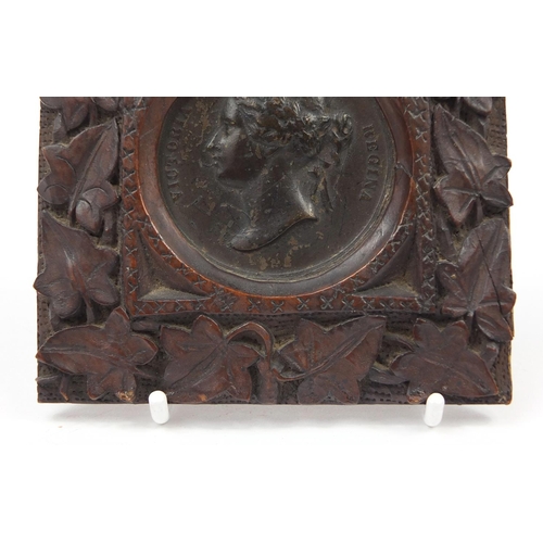 527 - Victorian Madras Exhibition bronze medallion housed in a Black Forest frame carved with foliage, 10c... 