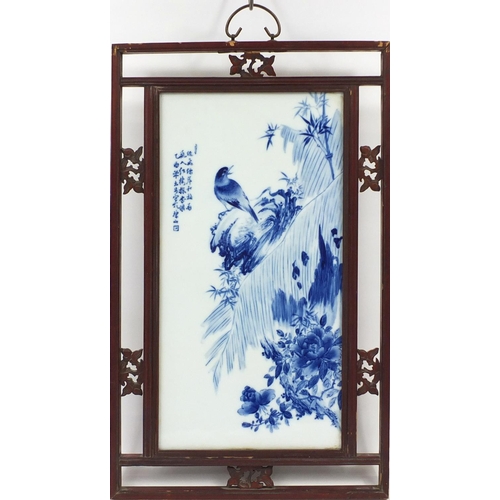 125 - Chinese blue and white panel housed in a carved hardwood frame, hand painted with a bird on a rock w... 