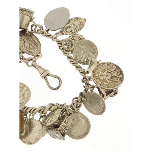 523 - Silver charm bracelet with a selection of mostly silver charms and coins, 87.0g