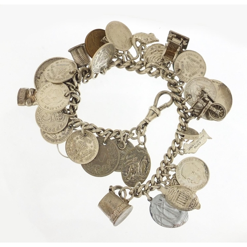 523 - Silver charm bracelet with a selection of mostly silver charms and coins, 87.0g