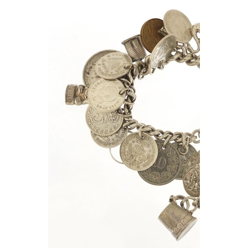 523 - Silver charm bracelet with a selection of mostly silver charms and coins, 87.0g