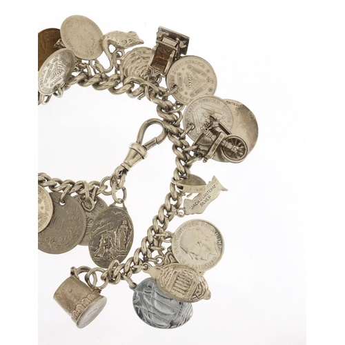 523 - Silver charm bracelet with a selection of mostly silver charms and coins, 87.0g