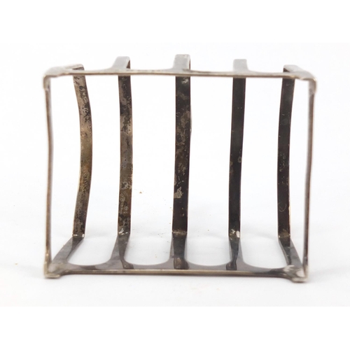 539 - Silver items comprising four slice toast rack, shell shaped dish and hand mirror, various hallmarks,... 