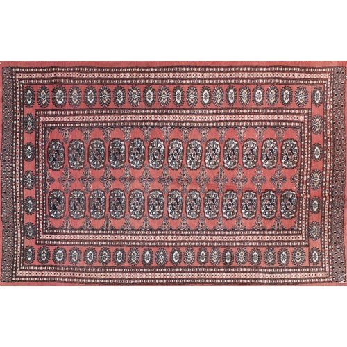 1315 - Pakistan wool rug with geometric design onto a salmon ground, 152cm x 100cm