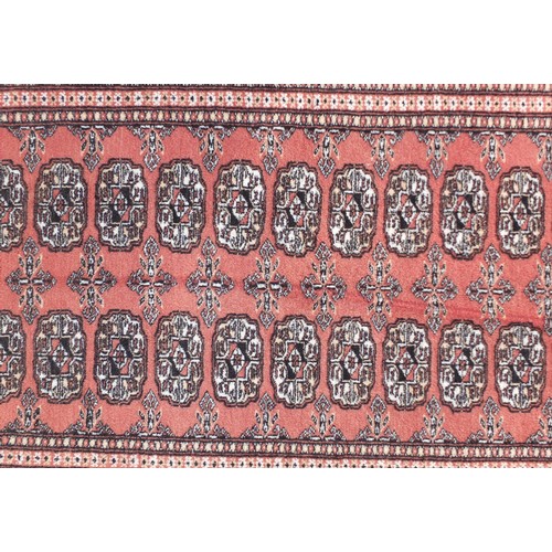 1315 - Pakistan wool rug with geometric design onto a salmon ground, 152cm x 100cm