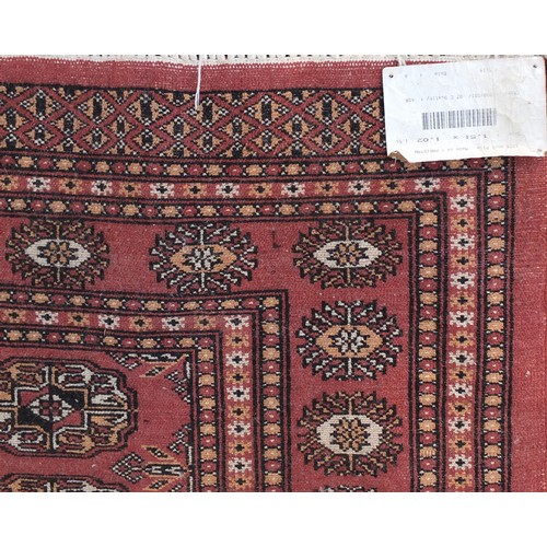 1315 - Pakistan wool rug with geometric design onto a salmon ground, 152cm x 100cm