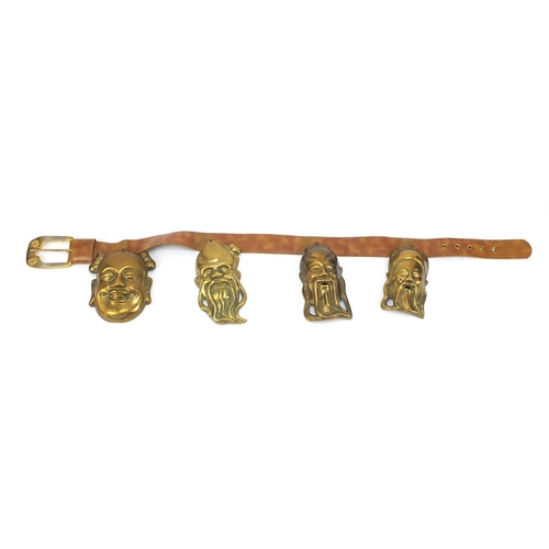 3780 - Leather belt housing four Chinese brass Emperor/Buddha heads, the largest head 16cm high