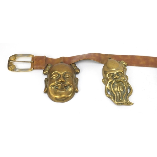 3780 - Leather belt housing four Chinese brass Emperor/Buddha heads, the largest head 16cm high