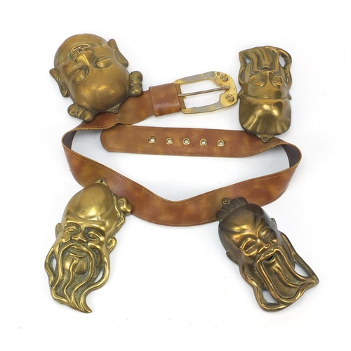 3780 - Leather belt housing four Chinese brass Emperor/Buddha heads, the largest head 16cm high