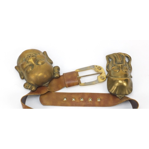 3780 - Leather belt housing four Chinese brass Emperor/Buddha heads, the largest head 16cm high