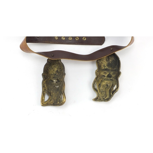 3780 - Leather belt housing four Chinese brass Emperor/Buddha heads, the largest head 16cm high