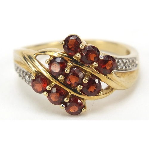 2354 - 9ct gold red stone crossover ring with diamond shoulders, size O, 2.9g