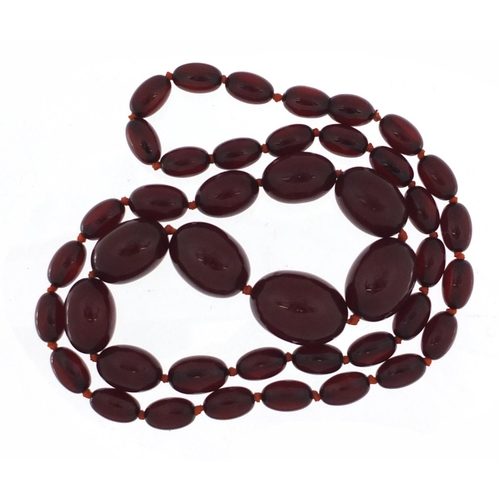 2389 - Cherry amber coloured bead necklace, 80cm in length, the largest bead 2.9cm in length, 81.0g