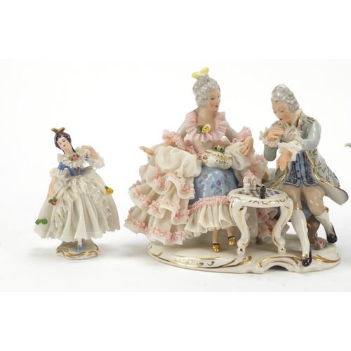 484 - Dresden, four German porcelain lace figurines including a group of a couple playing chess, the large... 