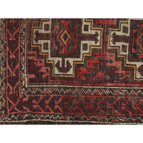 1556 - Rectangular Persian rug having a geometric repeat central field on to red grounds, 190cm x 99cm