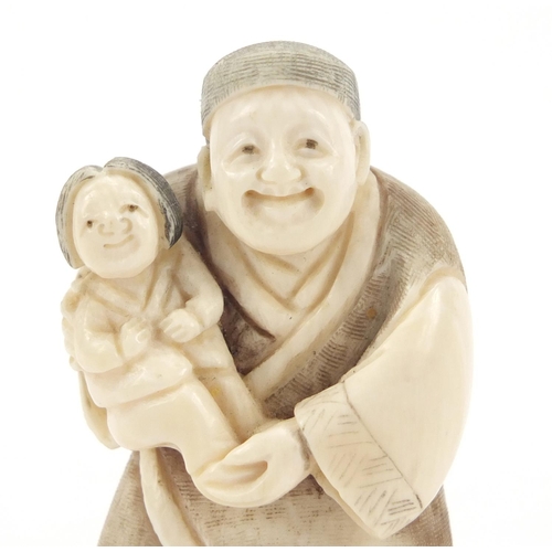 473 - Japanese carved ivory netsuke of a man holding a child, character marks to the base, 6.5cm high