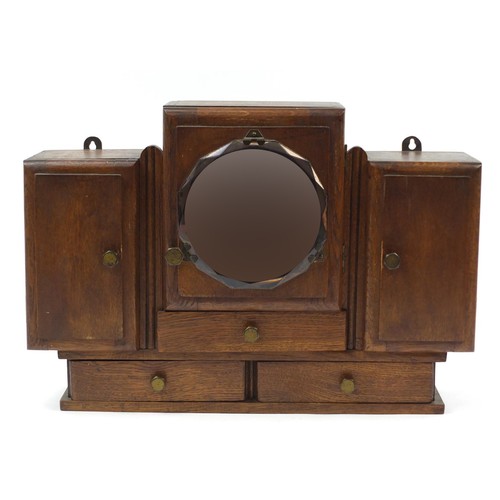 1510 - Art Deco oak wall hanging unit with bevelled peach glass mirror, having three cupboard doors above t... 