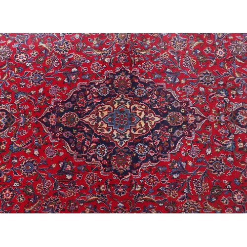 1509 - Rectangular Persian Kashan carpet with floral pattern onto a red and blue ground, 377cm x 295cm