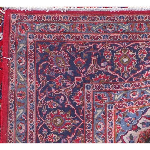 1509 - Rectangular Persian Kashan carpet with floral pattern onto a red and blue ground, 377cm x 295cm