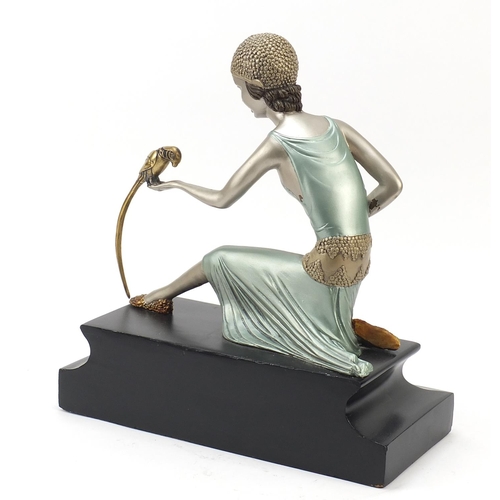 311 - Large painted metal sculpture of an Art Deco female holding a bird, raised on an ebonised wood block... 