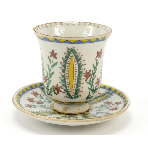 54 - Turkish Kutahya pottery cup and saucer hand painted with flowers, the cup 10cm high