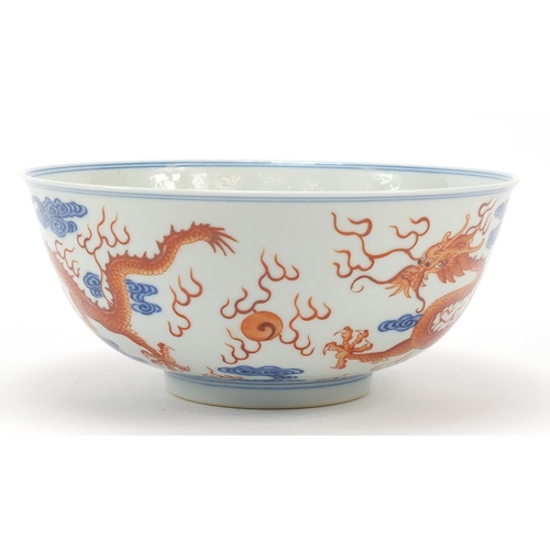 335 - Chinese blue and white with iron red porcelain bowl, finely hand painted with two dragons amongst cl... 