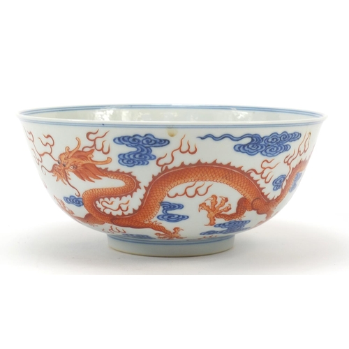 335 - Chinese blue and white with iron red porcelain bowl, finely hand painted with two dragons amongst cl... 