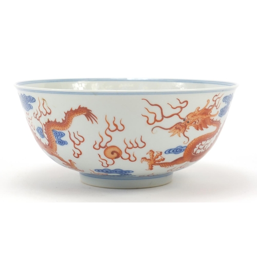 335 - Chinese blue and white with iron red porcelain bowl, finely hand painted with two dragons amongst cl... 