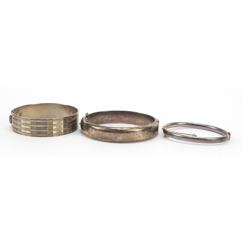 795 - Three silver hinged bangles including two Victorian style engraved with flowers, total 55.0g