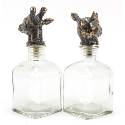 514 - Pair of glass decanters with bronzed rhinoceros and giraffe head stoppers, the largest 24.5cm high