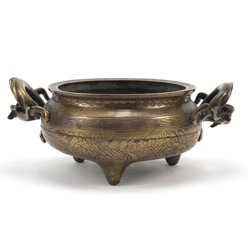 104 - Chinese patinated bronze tripod censer with twin dragon handles, four figure character marks to the ... 