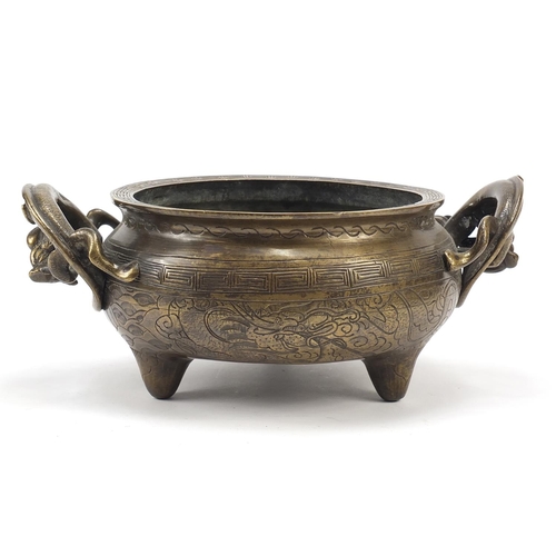 104 - Chinese patinated bronze tripod censer with twin dragon handles, four figure character marks to the ... 