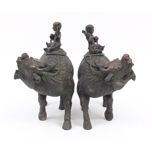 923 - Pair of Chinese patinated bronze incense burners, each in the form of a young boy holding a ruyi and... 