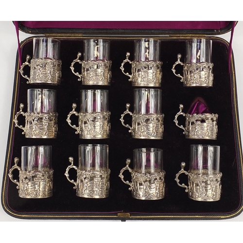 125 - Set of twelve Victorian silver glass holders embossed with cherubs at play and fitted with eleven gl... 