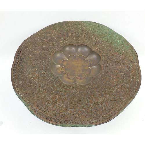 488 - Large Middle Eastern coppered brass tray top table embossed with foliage, 52cm high x 99cm in diamet... 