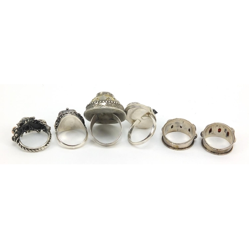 647 - Six Middle Eastern silver rings, some with hinged compartments and set with semi precious stones, va... 