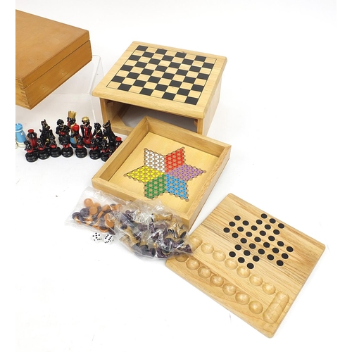 1243 - Two wooden games compendiums and a hand painted figural set, the largest 25cm wide