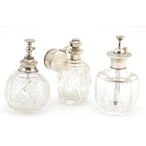 769 - Three cut glass perfume atomisers with hallmarked silver tops, the largest 11cm high