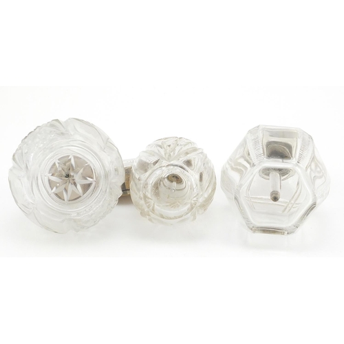 769 - Three cut glass perfume atomisers with hallmarked silver tops, the largest 11cm high