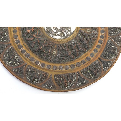 467 - Two Indian Tanjore brass, copper and silver plates, each embossed with a deity, birds and flowers, t... 