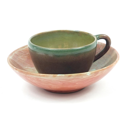 100 - Galileo Chini, Italian pottery cup and saucer having a green and red marbleised glaze, the saucer nu... 