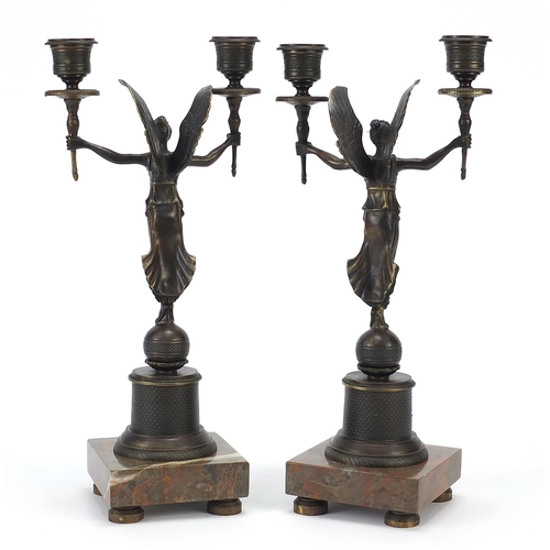 601 - Pair of classical patinated bronze figural two branch candlesticks raised on square marble bases, ea... 